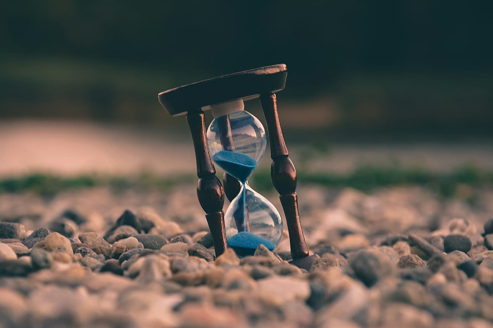 An hourglass resting on stones, sand mid-fall.