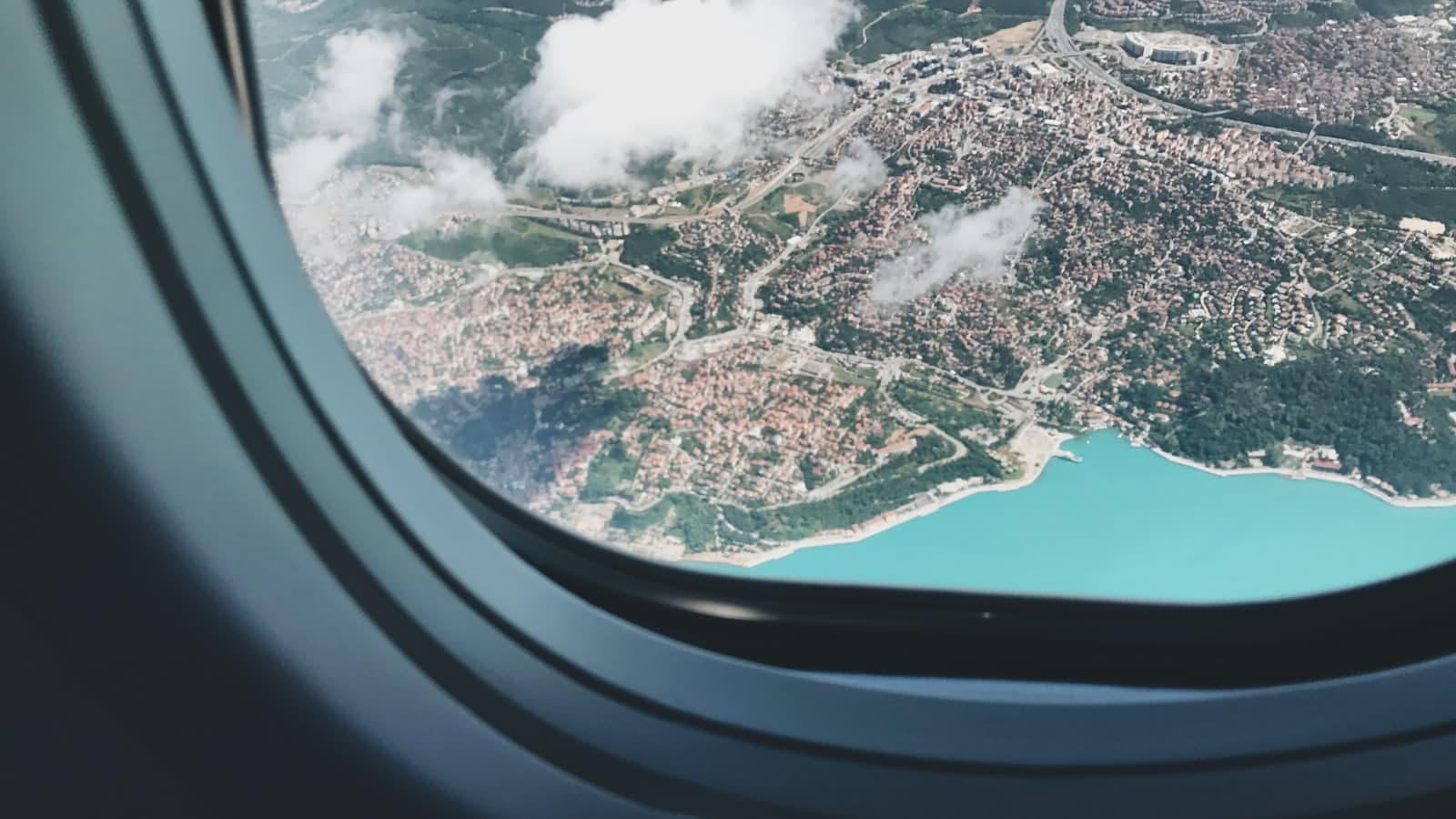 The view from an airplane window, looking down over a city far below at dusk.